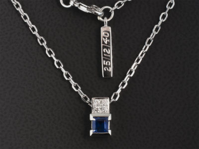 18kt White Gold Part Rub and Pave Set Sapphire and Diamond Pendant, Princess Cut Sapphire 0.47ct, 4x Round Brilliant Cut Diamonds 0.06ct F Colour SI Clarity Minimum on a 16 inch 18kt White Gold Angled Filed Trace Chain with Date Inscribed Tag Detail