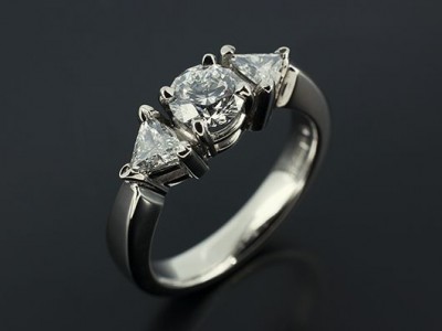 Round Brilliant 0.51ct E Colour SI1 Clarity with 0.23ct Total Trilliant Cut Diamonds in a Palladium Trilogy Setting.