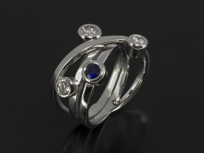 Round Brilliant Cut Diamonds, 0.49ct (3) & Round Brilliant Cut Sapphire Rub-over Set in 9kt White Gold in a Satellite Design