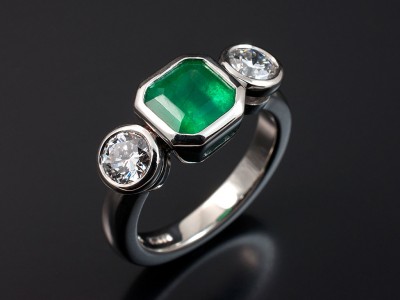 Emerald Cut Emerald 1.40ct with 2 x 0.40ct G SI1 Round Brilliant Diamonds in an 18kt White Gold Rub Over Setting