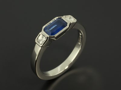 Emerald Cut Sapphire 0.63ct and Asscher Cuts Diamonds 0.18ct in a Palladium Trilogy Rub Over Set Design.