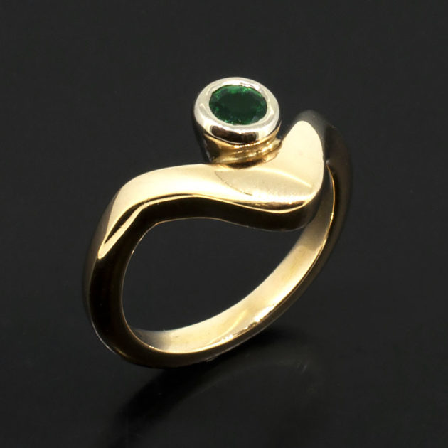 Ladies Solitaire Emerald Ring, Rub over Set Design in 18kt White and Yellow Gold, Round Emerald 0.10ct in an 18kt Rub over, Wave Design Detail