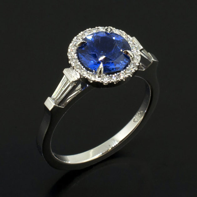 Round Brilliant Cut Sapphire 1.49ct with Tapered Baguette Cut Diamonds 0.20ct Total and Round Brilliant Cut Diamonds in a Platinum Halo Design Ladies Ring