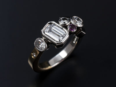 Ladies Diamond and Coloured Stone Dress Ring, 18kt White and Yellow Gold Asymmetrical Rub over Set Design, Emerald Cut Diamond 0.63ct, D Colour, VVS2 Clarity, Side Stones of Round Brilliant Cut Diamond, Oval Diamond and Pink Sapphire Precious Stones