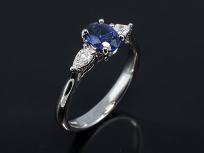 Platinum Claw Set Trilogy Design. Oval Cut Sapphire 1.00ct. Pear Shape Diamond, 0.28ct (2). F Colour, VS Clarity Minimum