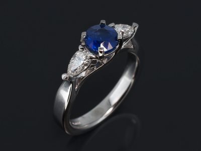 18kt White Gold Trilogy Design. Round Blue Sapphire, 1.25ct. Pear Cut Diamonds, 0.62ct (2), F Colour, SI Clarity.