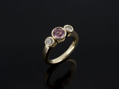 18kt Yellow Gold Trilogy Ring with Pink Peach Sapphire 5.5mm Centre Stone Rub over set