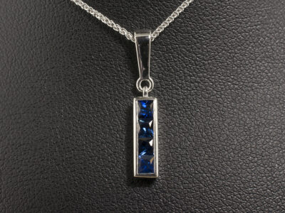 9kt White Gold Channel Set Sapphire Drop Pendant, Square Cut Sapphires 0.70ct Total on a 9kt White Gold Spiga Chain