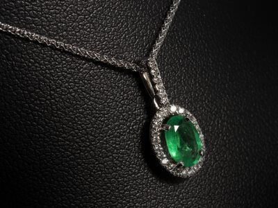 9kt White Gold Claw Set Emerald Pendant, Oval Cut Emerald 0.61ct., Round Brilliant Cut Diamond Halo and Bale (27) approx 0.13ct, F Colour, VS Clarity Min on a 9kt White Gold Spiga Chain 16-18 Inch