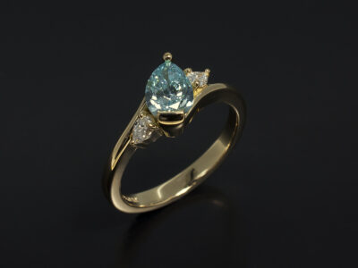 Ladies Coloured Diamond Trilogy Engagement Ring, 18kt Yellow Gold Claw and Part Rub Over Set Design, Pear Cut Blue Treated Diamond 0.70ct and Pear Cut Side Diamonds, Twist Band Detail