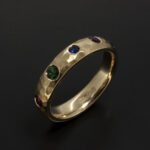 Ladies Eternity Ring, 9kt Yellow Gold Secret Set Design with Round Rubies, Sapphire and Emeralds in a Hammered Finish