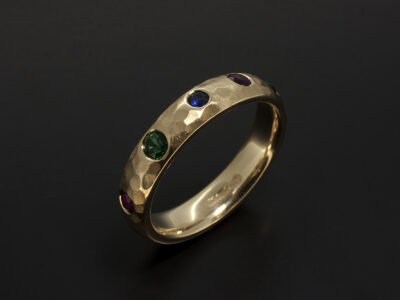 Ladies Eternity Ring, 9kt Yellow Gold Secret Set Design with Round Rubies, Sapphire and Emeralds in a Hammered Finish