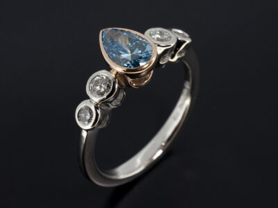 Ladies Blue Diamond 5 Stone Dress Ring, Platinum and 18kt Rose Gold Rub over Set Design, Pear Shape Fancy Vivid Blue Lab Grown Diamond 0.66ct, VVS2 Clarity. VG Polish, VG Symmetry, Round Brilliant Cut Diamonds 0.23ct (2), 0.13ct (2)