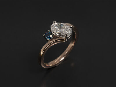 Ladies Blue Diamond Engagement Ring, Platinum and Rose Gold Claw Set Twist Design, Oval Cut Diamond 0.85ct, E Colour, VS2 Clarity, Ex Polish, Ex Symmetry, Round Brilliant Cut Blue Treated Diamond 0.10ct