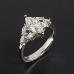 Ladies Diamond and Sapphire Engagement Ring, Platinum Claw Set Design, Marquise Cut Diamond 0.70ct, E Colour, SI1 Clarity, Marquise Cut Diamond Side Stones 0.34ct Total, Round Brilliant Cut Sapphires x2