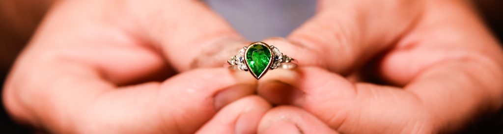 A naturally coloured Zambian emerald is the star attraction in this bespoke engagement ring by Blair and Sheridan - mixed metals and additional diamonds complete the design.